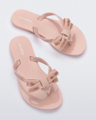 Top view of a pair light pink Harmonic M Lover kids flip flops with Melissa logo on bow