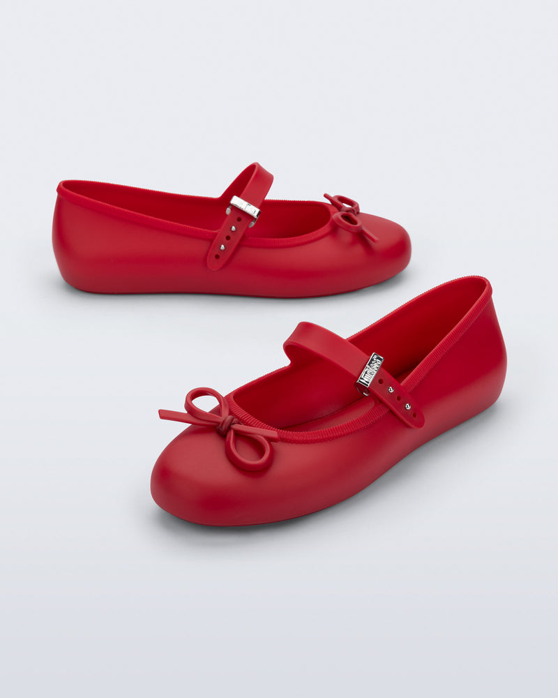 Side and angled view of a pair of red Soft Ballerina Delicate Bow flats with top strap and bow