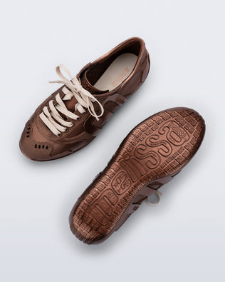 Top and bottom view of a pair of bronze Motion sneakers with beige laces