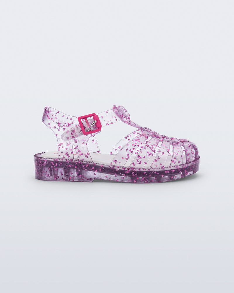 Side view of a clear Possession Elements baby sandal with pink glitter hearts