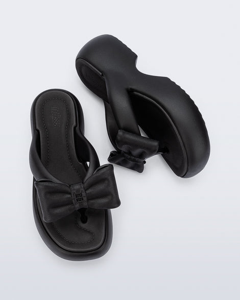 Side and top view of a pair of black Free Fuzzy Platform flip flops