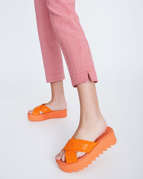 Model's legs wearing a pair of beige M Lover Cross Strap platform slides