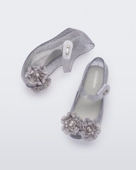 Side and top view of a pair of clear grey glitter Ultragirl Springtime baby flat with grey flower and peep toe.