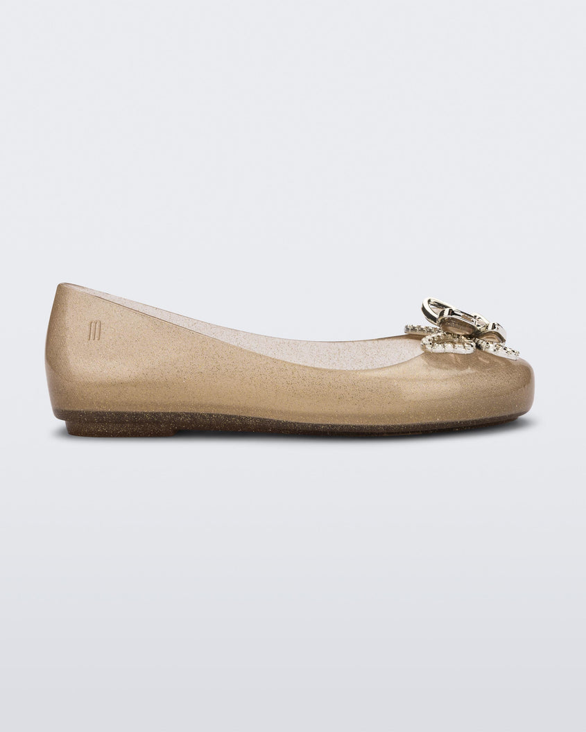 Side view of a glitter beige Mini Melissa Sweet Love Butterfly flat with a gold butterfly detail on the toe