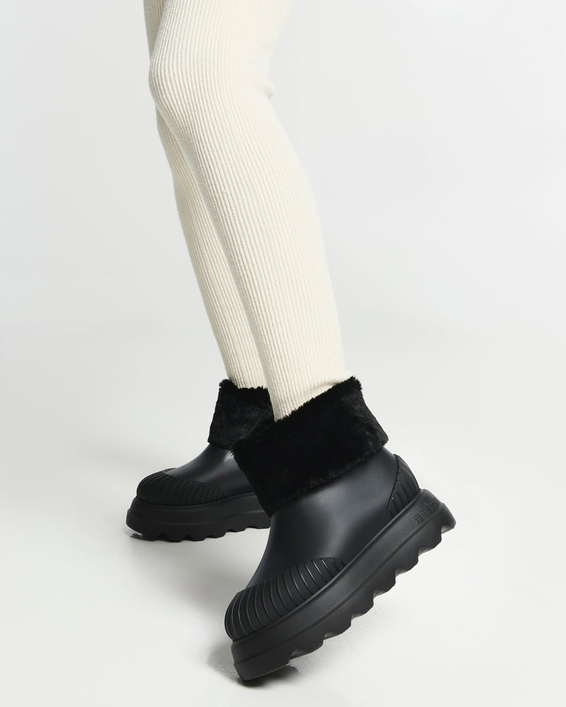 Model's leg in cream leggings wearing a pair of Warm Boots with fuzzy cuff and insole