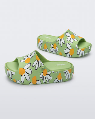Angled view of a pair of green Free Print Platform slides with a white and yellow flower print.