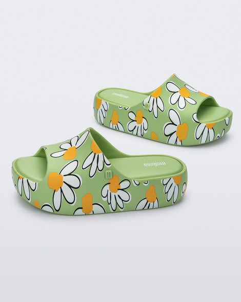 Angled view of a pair of green Free Print Platform slides with a white and yellow flower print.