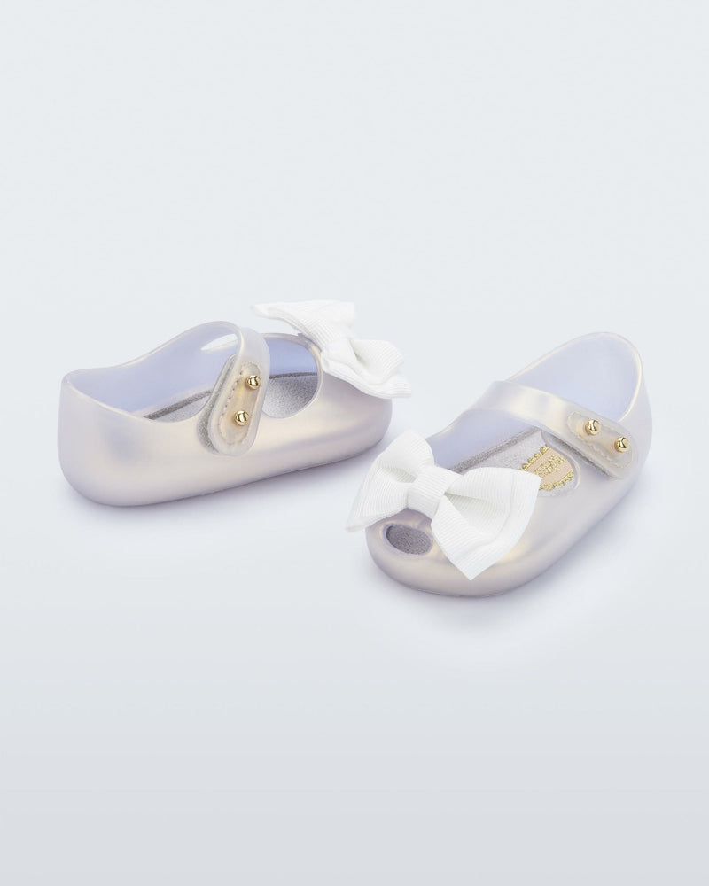 Angled view of a pair of pearly white My First Melissa mary jane with a bow.
