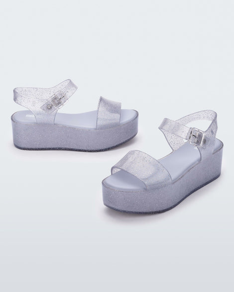 An angled front and side view of a pair of glitter lilac Melissa platform sandals with a front and ankle strap