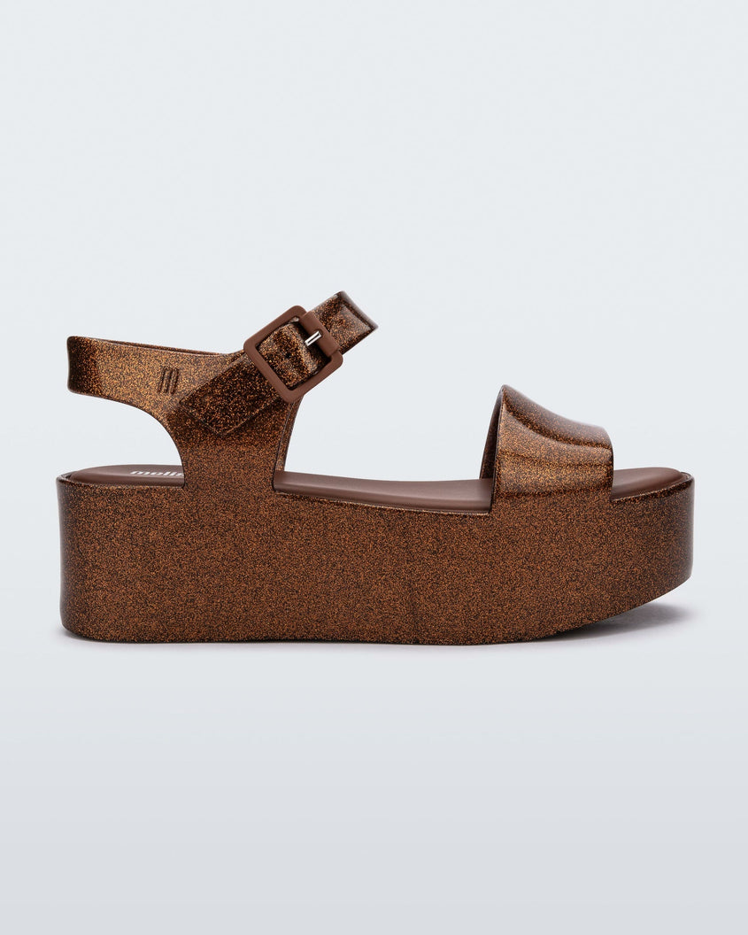 Side view of a bronze Melissa platform sandal with a front and ankle strap