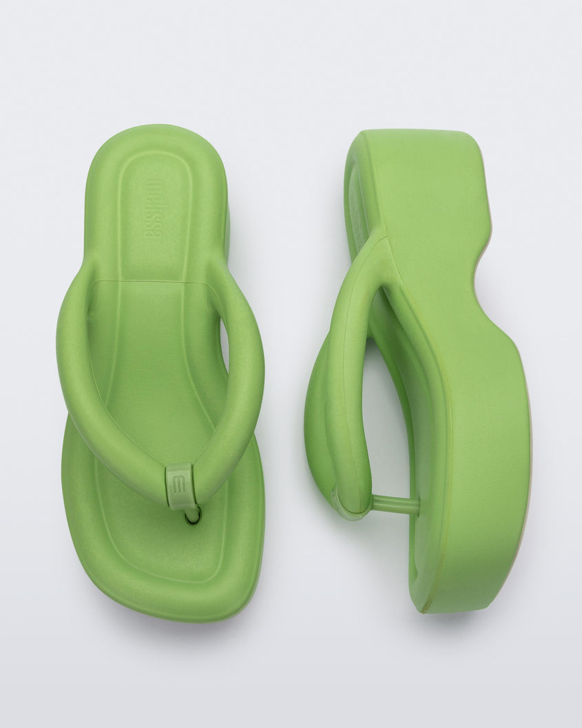 Top and side view of a pair of Melissa Free platform flip flops in lime green with grey soles