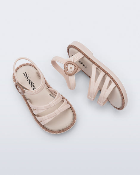 Side and top view of a pair of beige Aurora baby sandals with brown trim and buckle