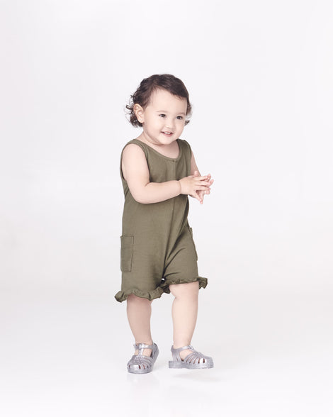 A model posing wearing a pair of Mini Melissa Possession baby sandals in glitter clear with velcro buckle closure on the ankle straps