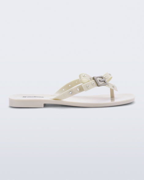 Side view of a beige Harmonic Squared flip flop with bow on strap