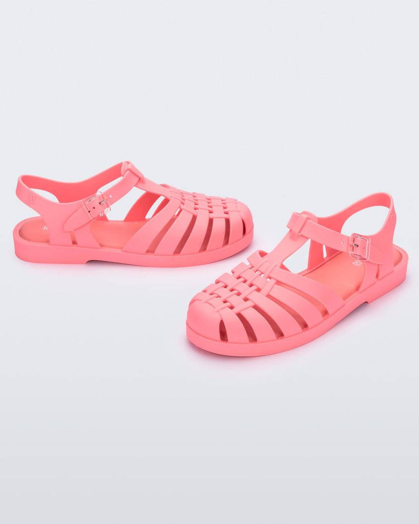 Angled view of avpair of coral pink Melissa Possesion sandal.