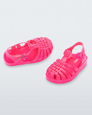 An angled front and top view of a pair of pink Mini Melissa Possession sandals with several straps and a closed toe front.