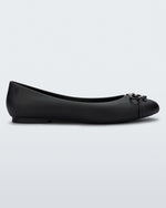 Side view of a black Melissa flat with a black bow detail with metallic accents on the toe