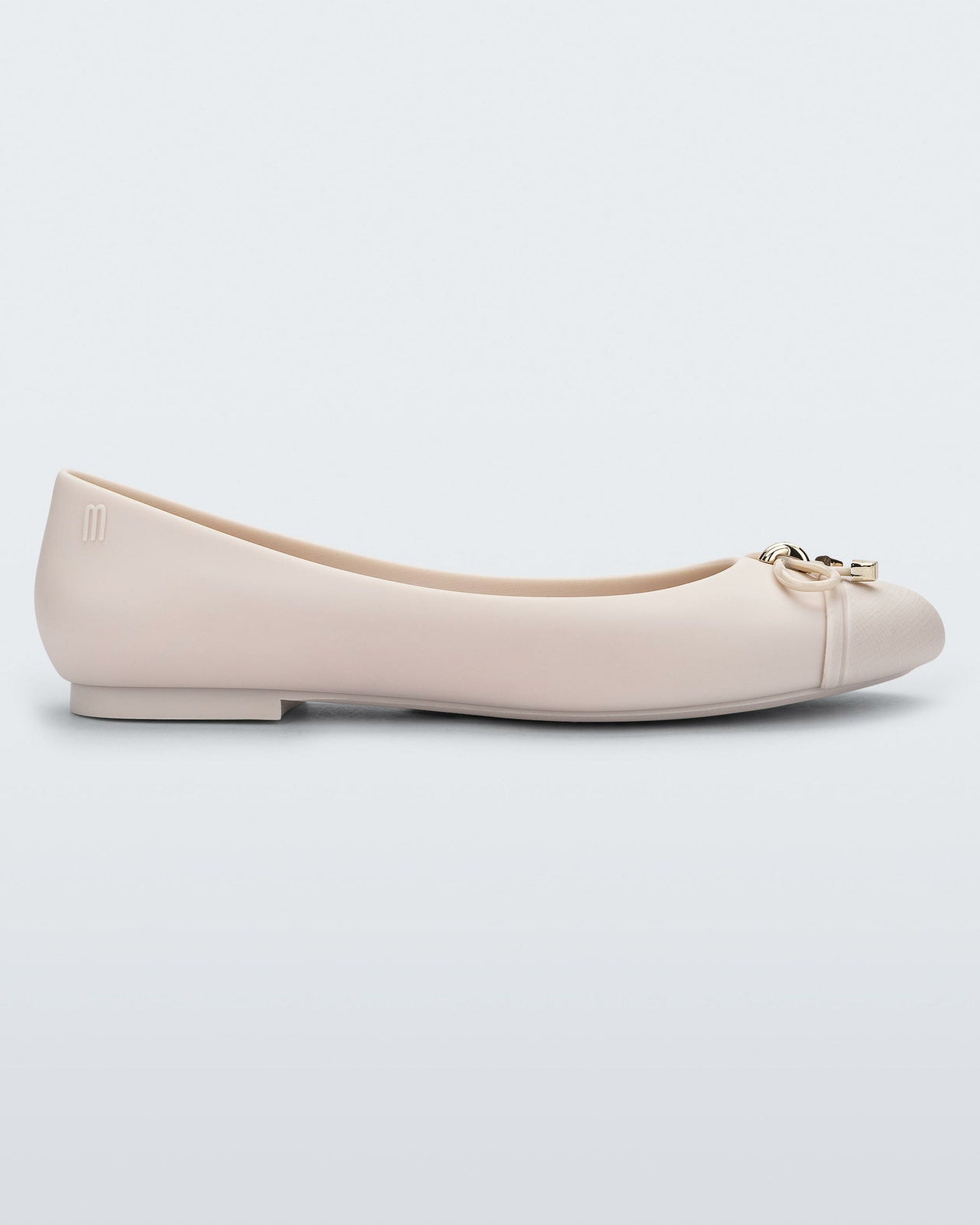 Side view of a light beige Melissa flat with a beige bow detail with gold accents on the toe