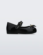 An outter side view of a black Mini Melissa Sweet Love flat with a top strap and a bow detail on the toe.