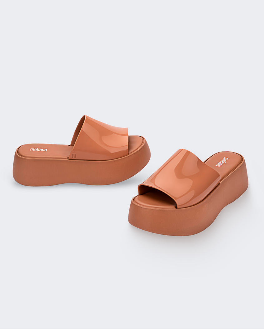 An angled front and side view of a pair of beige Melissa Becky platform slides