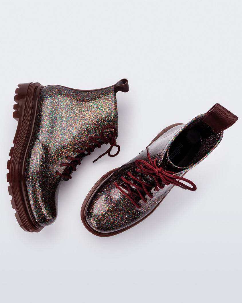 Side and top view of a pair of black/multicolor glitter Melissa Coturno boots.