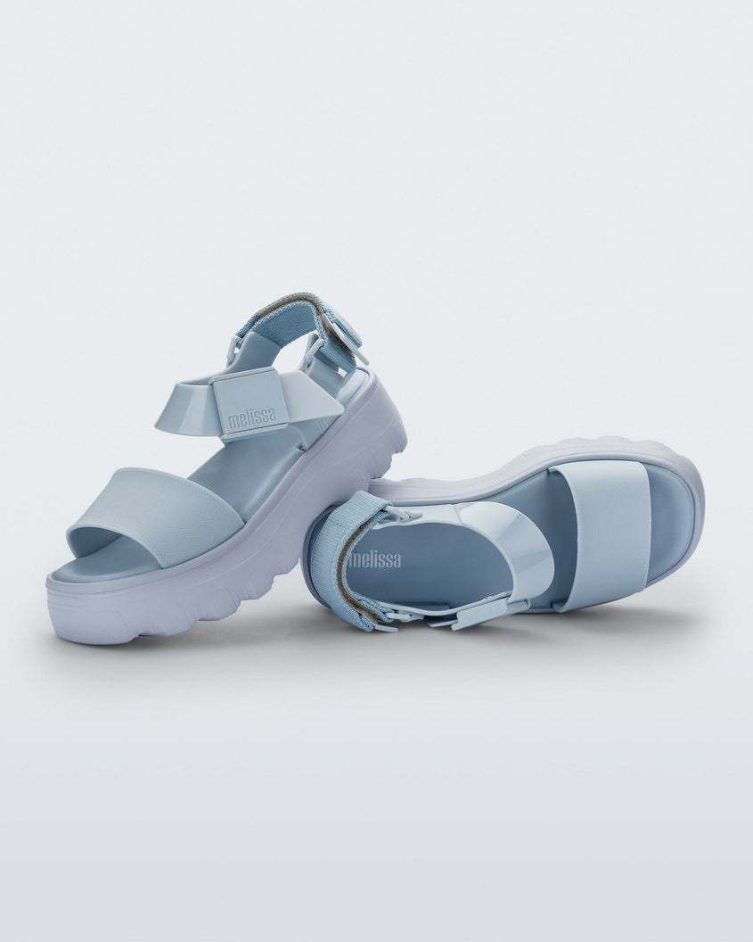 An angled top and side view of a pair of light blue Melissa Kick Off platform sandals, leaning on eachother, with a front and ankle strap