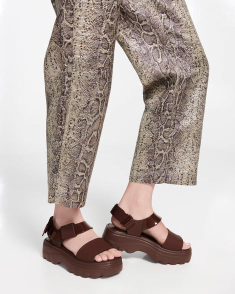Model's legs in snake print pants wearing a pair of brown Kick Off Sandals