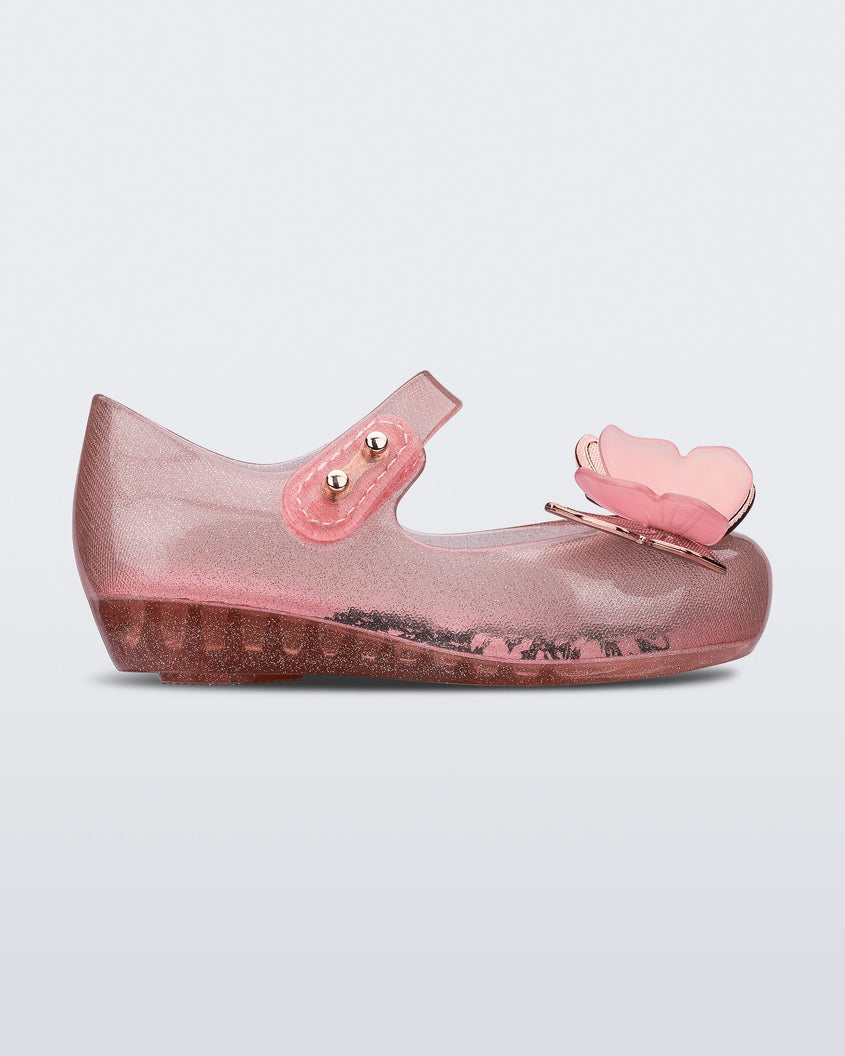 Side view of a glitter clear pink Mini Melissa Ultragirl Butterfly baby mary jane flat with two pink metallic and clear butterflies and peep toe.