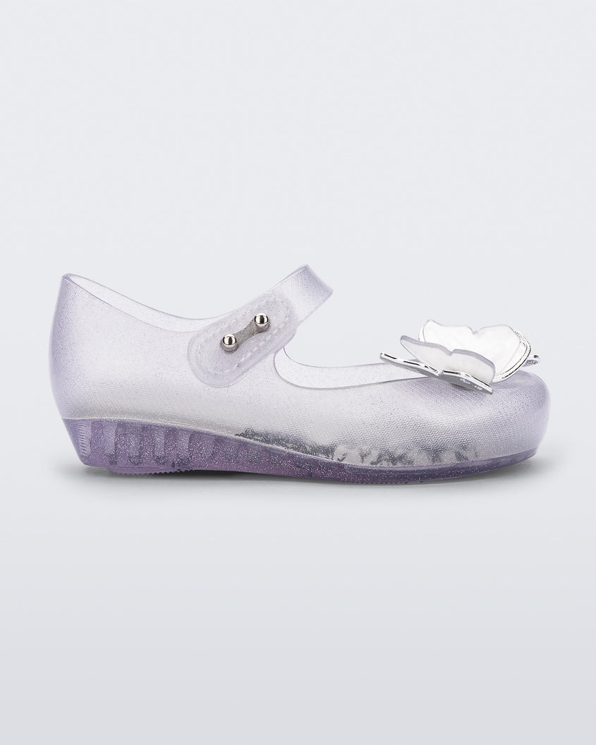 Side view of a clear glitter Mini Melissa Ultragirl Butterfly baby mary jane flat with two metallic and clear butterflies and peep toe.