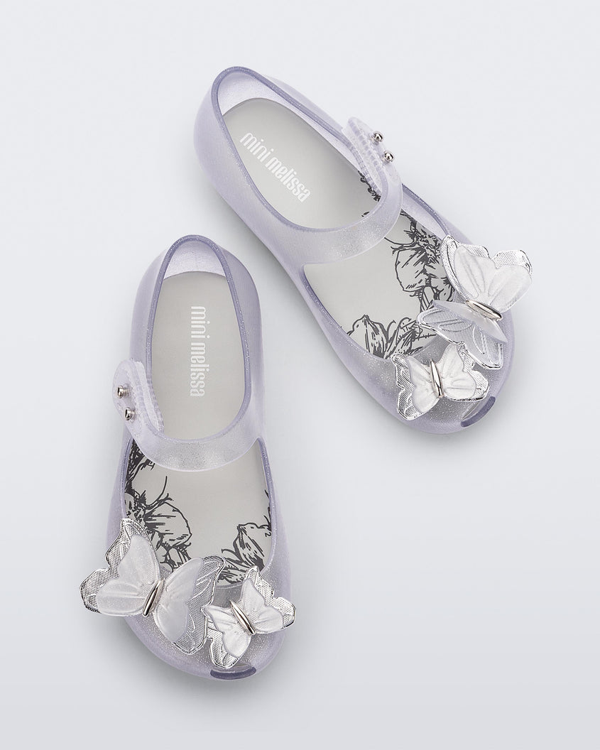 Top view of a pair of clear glitter Mini Melissa Ultragirl Butterfly baby mary jane flats with two metallic and clear butterflies and peep toe.