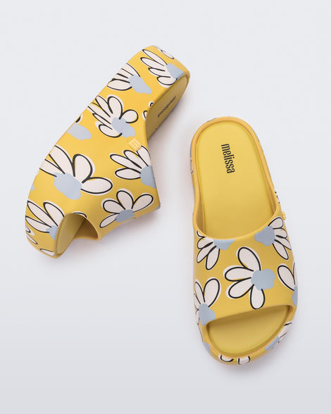 Side and top view of a pair of yellow Free Print Platform slides with a white and blue flower print.