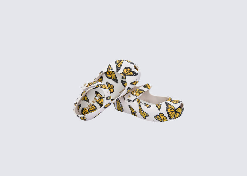 Top and angled view of a pair of white Ultragirl Print baby ballerinas with orange and black butterflies