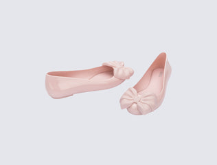 Side and angled view of a pair of pink Sweet Love flats with bow on top