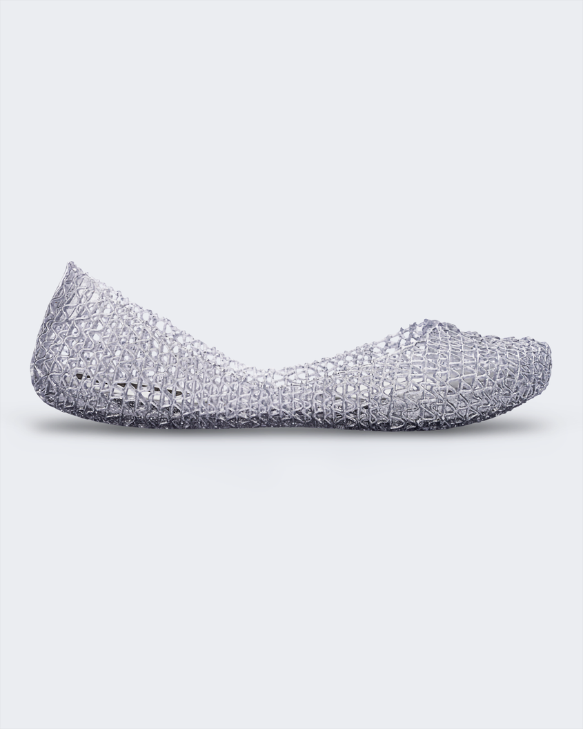 An outer side view of a glitter silver Melissa Campana flat with a distinctive interwoven pattern