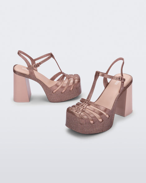 Side and angled view of a pair of pink glitter Melissa Party platform heels. 