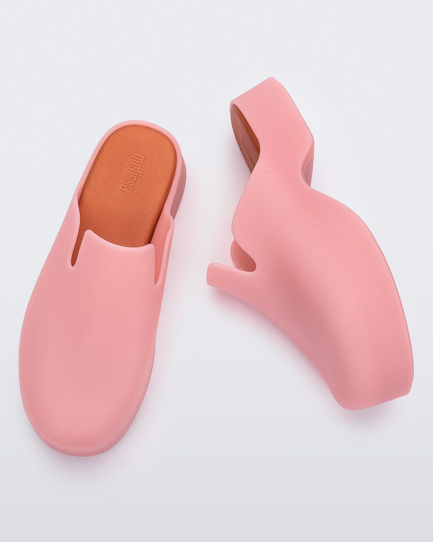 Top and side view of a pair of pink Melissa Zoe mules with orange insoles.