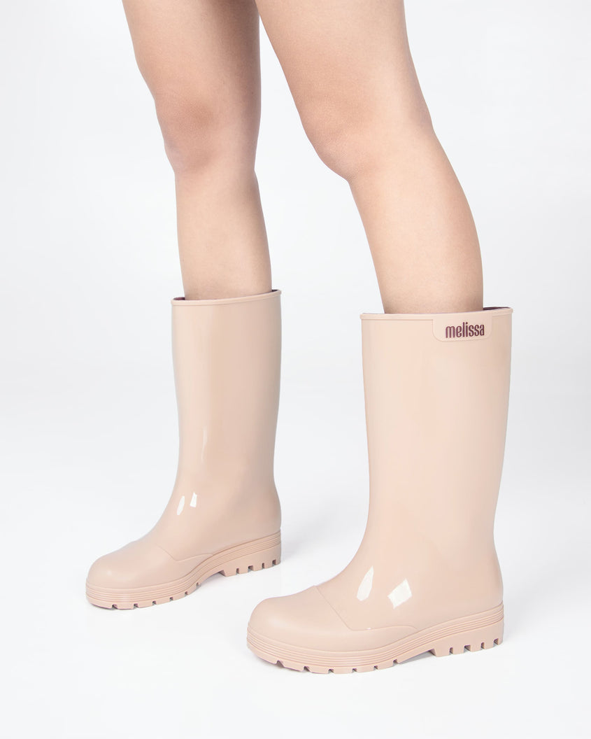 Models legs wearing a pair of beige Melissa Welly boots.