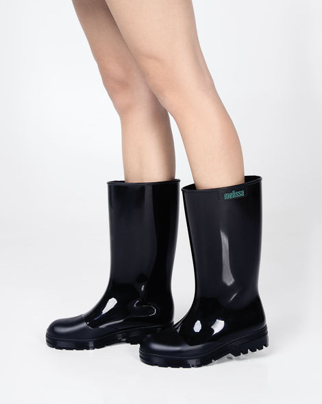 Models legs wearing a pair of black Melissa Welly boots.