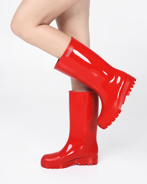 Models legs wearing a green of red Melissa Welly boots.