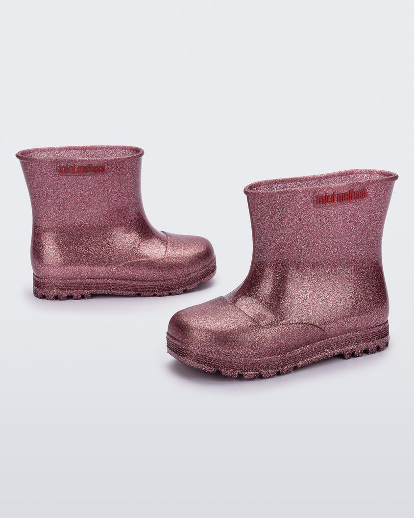 Angled view of a pair of glitter pink baby Melissa Welly boots.