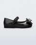 Side view of a black Mini Melissa Sweet Love baby mary jane flat with a metallic gray bow.