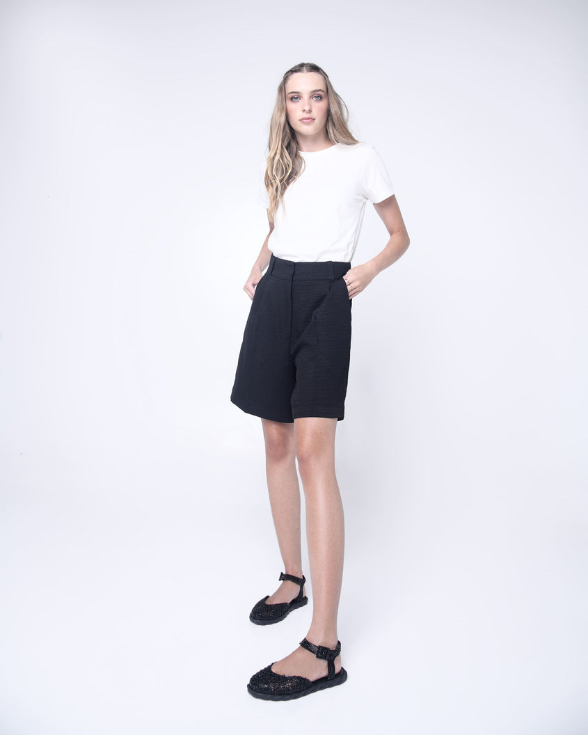 Model in a white shirt and black skirt wearing a pair of black Melissa Papel Espadrille Campana sandals with braided sole detail and ankle strap