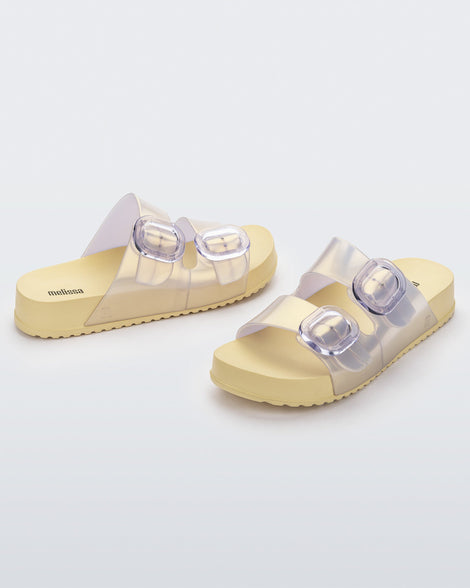Front and back angled view of a pair of pearly yellow Cozy slides with two buckles.
