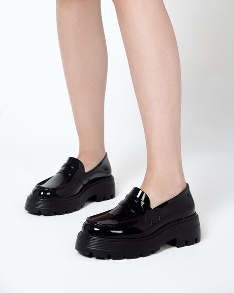 Closeup view of a model wearing a pair of Melissa Royal platform loafers in Black