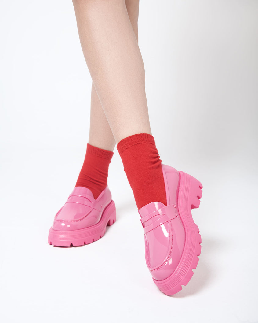 Closeup view of a model wearing a pair of red ankle socks and the Melissa Royal platform loafers in Pink