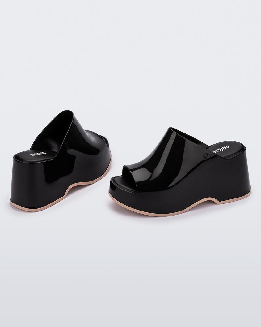 Angled view of a pair of Black Melissa Patty platform mules with beige outsoles.
