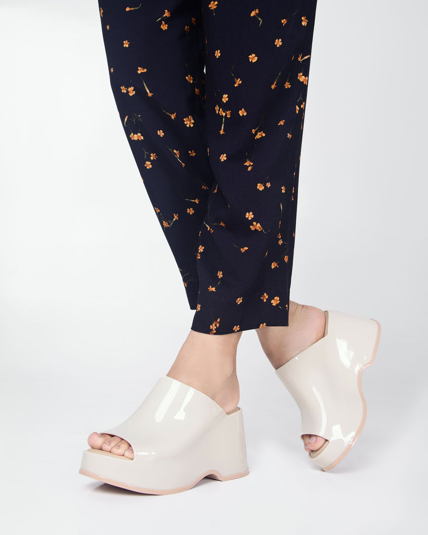Model's legs wearing a pair of beige Melissa Patty platform mules.