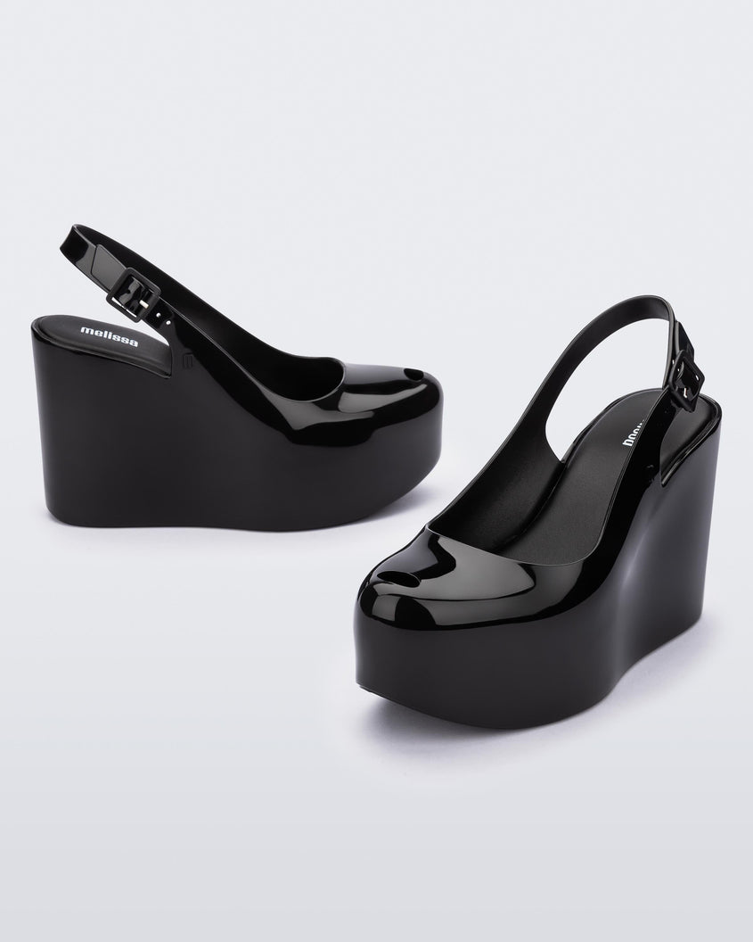 Side and angled view of a pair of black Melissa Groovy wedge platform slingback heels with peep toe.