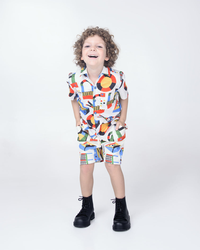 A child model in a patterned shirt and shorts wearing a pair of black Melissa Coturno boots.