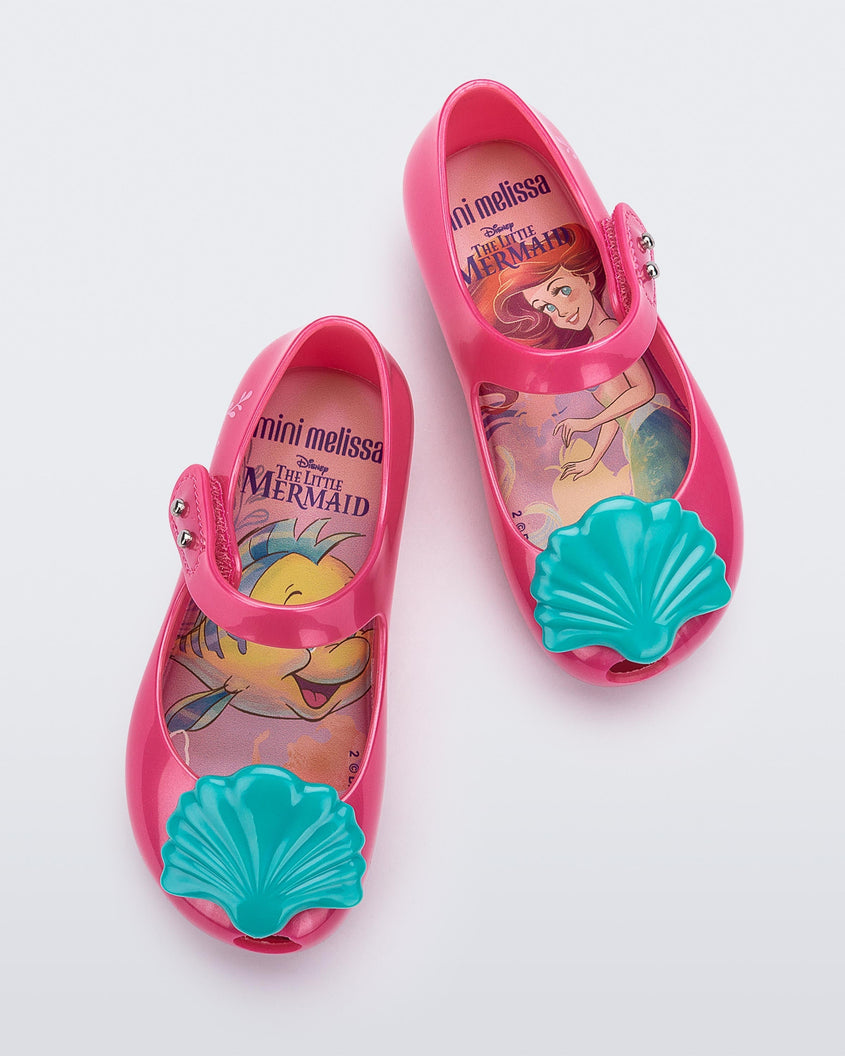 Top view of a pair of pink Mini Melissa Ultragirl + Disney Little Mermaid flats with blue shell on top